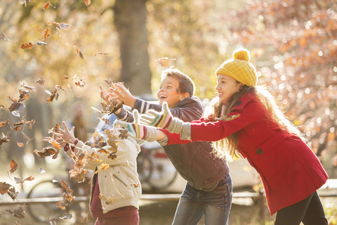 Jungen und Mädchen, die Herbstblätter fangen, lizenzfreies Stockfoto