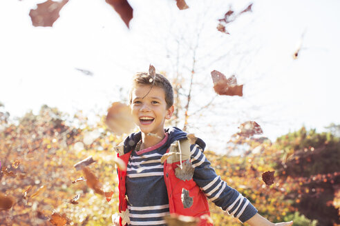 Porträt eines begeisterten Jungen, der Herbstblätter wirft - HOXF00561