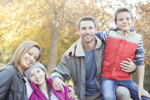 Porträt lächelnde Familie vor einem Baum mit Herbstlaub, lizenzfreies Stockfoto