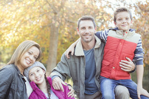 Porträt lächelnde Familie vor einem Baum mit Herbstlaub - HOXF00567