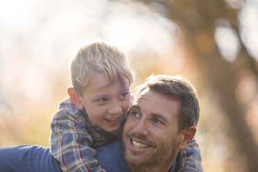 Vater und Sohn nehmen sich liebevoll Huckepack - HOXF00569