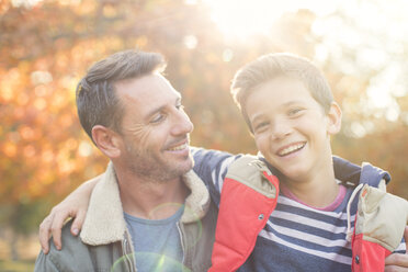 Portrait smiling father and son in front of autumn leaves - HOXF00570