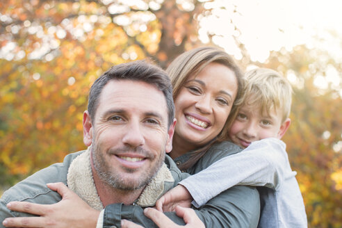 Porträt lächelnd Familie umarmen vor Herbstlaub - HOXF00577