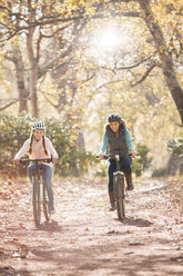 Mutter und Tochter fahren mit dem Fahrrad auf einem Weg im Wald - HOXF00580