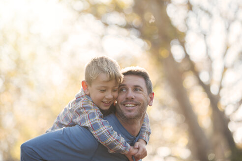 Vater und Sohn nehmen sich liebevoll Huckepack - HOXF00581