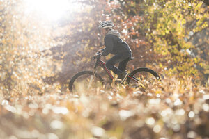 Junge Fahrradfahren im Wald mit Herbstlaub - HOXF00587