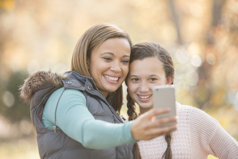 Mutter und Tochter nehmen Selfie mit Kamera-Handy im Freien, lizenzfreies Stockfoto