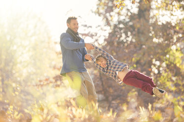 Vater spinnt Sohn zwischen Herbstblättern - HOXF00597