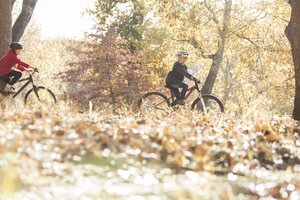 Junge und Mädchen Radfahren im Wald mit Herbstlaub - HOXF00604