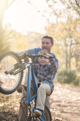 Vater bringt seinem Sohn bei, wie man im Wald einen Wheelie macht - HOXF00614