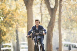 Lächelnder Junge beim Fahrradfahren im Park - HOXF00622