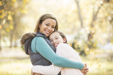 Porträt einer lächelnden Mutter und ihrer Tochter, die sich im Freien umarmen - HOXF00624
