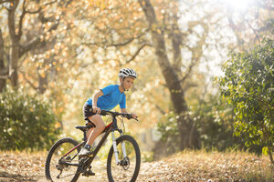 Junge fährt Mountainbike auf einem Waldweg - HOXF00630