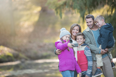 Familie macht Selfie mit Fotohandy im Wald, lizenzfreies Stockfoto