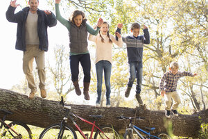 Begeisterte Familie springt von umgestürztem Baumstamm über Fahrräder - HOXF00645