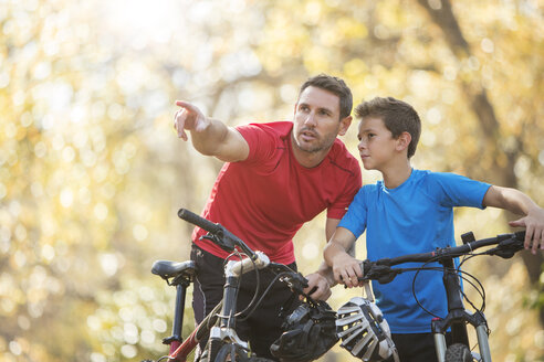 Vater zeigt und erklärt dem Sohn auf dem Mountainbike - HOXF00650