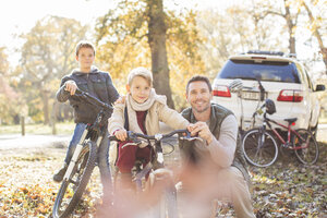 Portrait Vater und Söhne mit Fahrrädern im Herbstpark - HOXF00651