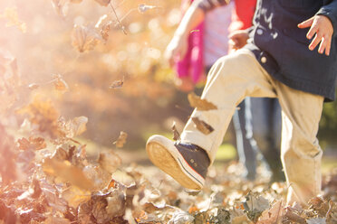 Boy running and jumping in autumn leaves - HOXF00655