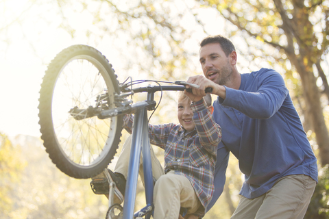 Vater bringt Sohn Wheelie auf dem Fahrrad bei, lizenzfreies Stockfoto