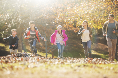 Familie läuft im Park mit Herbstlaub, lizenzfreies Stockfoto