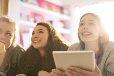 Teenage girls using digital tablet looking up - HOXF00674