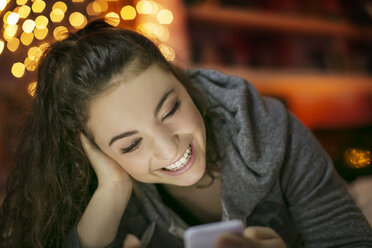 Lächelndes Teenager-Mädchen, das mit seinem Handy SMS schreibt - HOXF00683
