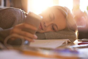 Teenage girl laying and texting with cell phone - HOXF00686