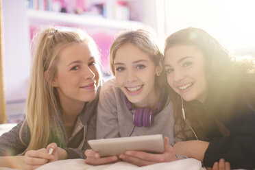 Portrait of smiling teenage girls using digital tablet - HOXF00690