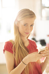 Porträt blondes Teenager-Mädchen, das eine SMS mit Handy schreibt - HOXF00695