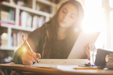 Teenager-Mädchen mit digitalem Tablet bei den Hausaufgaben am sonnigen Schreibtisch - HOXF00697