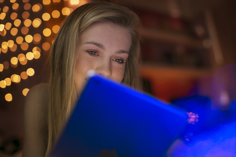 Teenager-Mädchen benutzt digitales Tablet in einem dunklen Raum, lizenzfreies Stockfoto