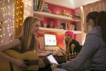 Teenager-Mädchen spielen Gitarre und benutzen ein digitales Tablet im Schlafzimmer - HOXF00712