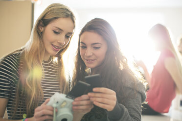 Teenage girls using instant camera - HOXF00714