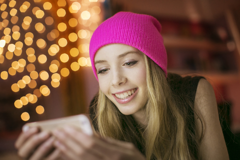 Teenager-Mädchen mit rosa Mütze schreibt SMS mit Handy, lizenzfreies Stockfoto