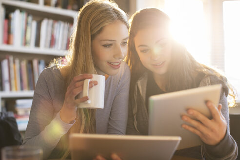Mädchen im Teenageralter trinken Kaffee und benutzen digitale Tablets - HOXF00722