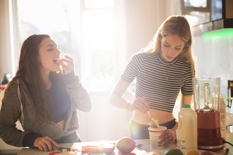 Teenager-Mädchen machen Smoothie in der sonnigen Küche, lizenzfreies Stockfoto