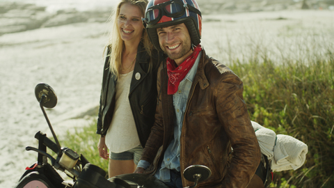 Portrait lächelndes junges Paar auf Motorrad am Strand, lizenzfreies Stockfoto