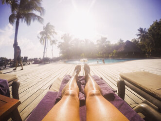 Woman sunbathing at sunny tropical poolside - HOXF00797