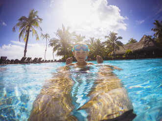 Portrait lächelnder Junge im sonnigen tropischen Schwimmbad - HOXF00801