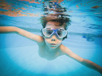Porträt eines Jungen, der im Schwimmbad unter Wasser schwimmt - HOXF00808