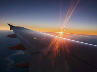 Sonnenuntergang hinter Flugzeugflügel im Himmel - HOXF00814