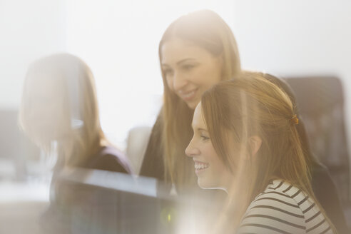 Lächelnde Geschäftsfrauen arbeiten in einem sonnigen Büro - HOXF00905