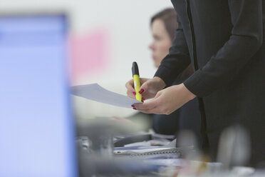 Geschäftsfrau hebt Papierkram im Büro hervor - HOXF00914