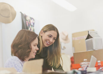 Smiling fashion buyers working at laptop in office - HOXF00937