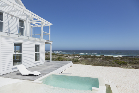 Strandhaus mit Pool und Terrasse mit Blick auf den Ozean bei strahlend blauem Himmel, lizenzfreies Stockfoto