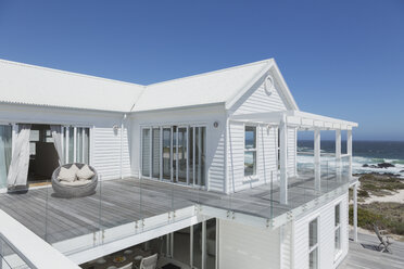 White beach house with balcony with ocean view under sunny blue sky - HOXF00953