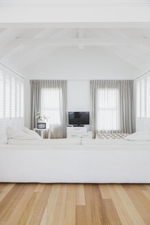 Weißes Wohnzimmer mit gewölbter Holzbalkendecke in einem Musterhaus - HOXF00956