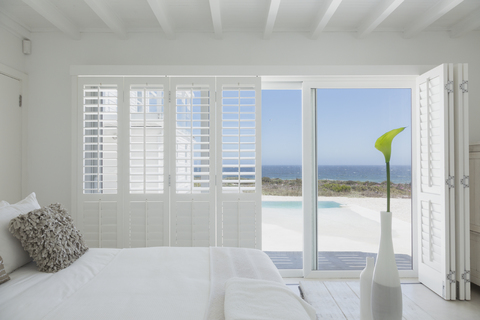 White bedroom home showcase open to swimming pool and ocean view stock photo