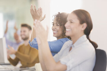 Businesswomen smiling and clapping in meeting - HOXF00998