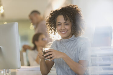 Portrait smiling businesswoman drinking coffee in office - HOXF01011